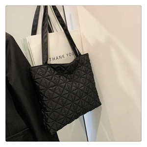 Close-up of black quilted tote bag with star patterns and dual shoulder straps
