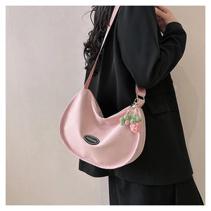 Detail of pink canvas crescent bag with fashion patch and handmade strawberry charm