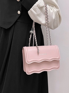Pink crossbody chain bag with scalloped flap and silver metal strap shown on model