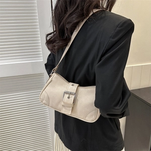 Minimalist creamy white leather shoulder bag with silver buckle worn by a model