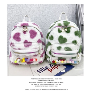 Détail de sacs à dos en peluche cœur avec poches PVC et pompons colorés décoratifs