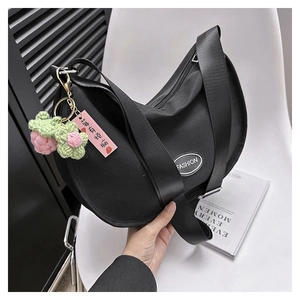 Detail of black crescent oxford bag with wide strap and cute strawberry charm