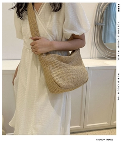 Detail of bohemian straw hobo bag showing natural woven texture and wide shoulder strap