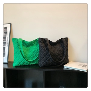 Close-up of quilted tote bags in green and black with geometric star stitching details