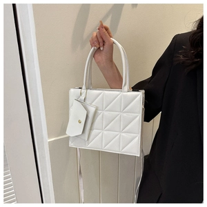 Close-up of a white quilted crossbody bag with a mini pouch and detachable strap