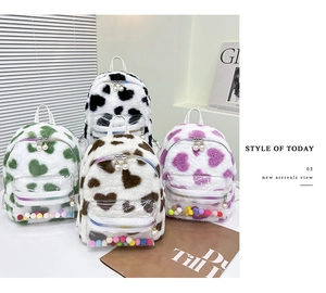 Détail de mini-sacs à dos en peluche avec motifs de cœur, imprimé vache et poches en PVC