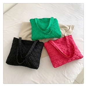 Flat lay of geometric quilted tote bags in green, black, and pink colors on white cloth