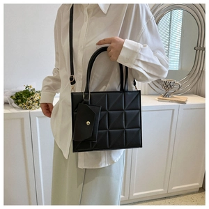 Detail of black quilted crossbody bag with matching mini pouch and adjustable strap