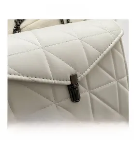 Détail du sac bandoulière matelassé blanc montrant le fermoir rotatif en métal