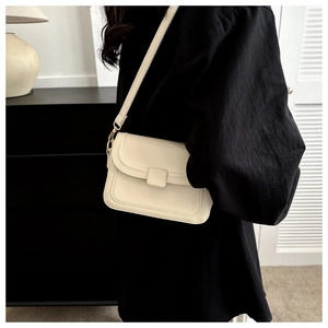 Minimalist cream white crossbody bag shown on model with adjustable strap and gold hardware