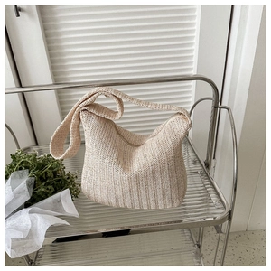 Detail of beige woven straw tote bag featuring intricate V-shape texture and top zipper