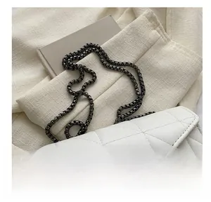 Gros plan sur un sac bandoulière blanc matelassé avec une bandoulière en chaîne foncée