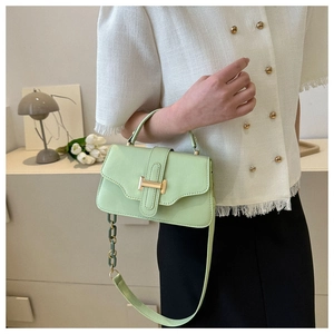 Detail of mint green square bag with gold H-clasp and decorative thick chain