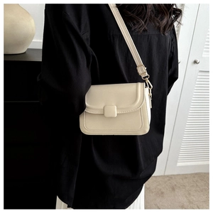 Detail showing cream-white flap bag with adjustable strap and gold metal hardware