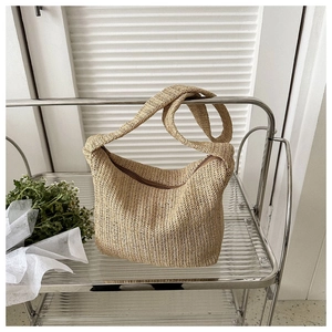 Close-up of bohemian woven straw hobo bag with zipper on a modern metallic display