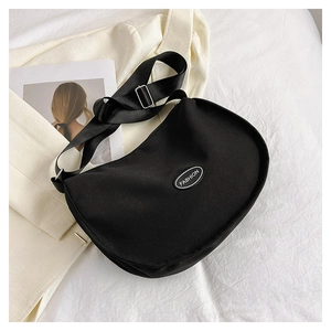Detail of black crescent oxford cloth bag featuring white FASHION patch and wide strap