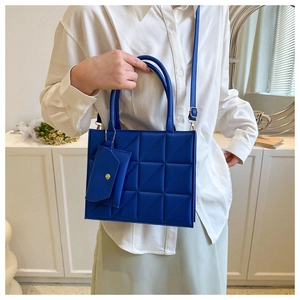 Detail view of the geometric quilted texture and mini pouch on the blue crossbody bag
