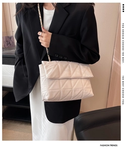 Elegante borsa a tracolla trapuntata beige con catena metallica indossata da una modella