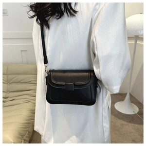 Minimalist black PU leather crossbody bag worn by model in a modern indoor setting