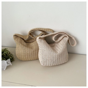 Detail of hand-woven straw tote bag with intricate herringbone pattern and zipper