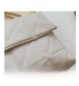 Dettaglio borsa trapuntata beige con cuciture rifinite e tracolla a catena