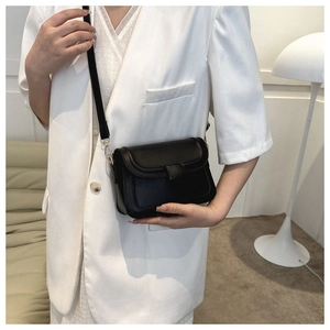 Detail of minimalist black crossbody bag with gold metal hooks and slim strap