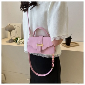 Detail view of pink crossbody square bag with gold buckle and chain on shoulder