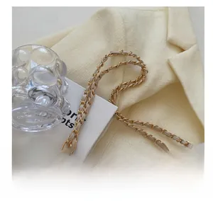 Dettaglio dell'elegante tracolla a catena con metallo dorato e similpelle beige della borsa