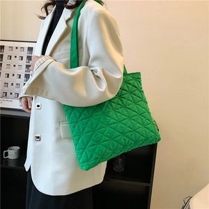 Green quilted tote bag with diamond stitching and wide strap shown from a side view