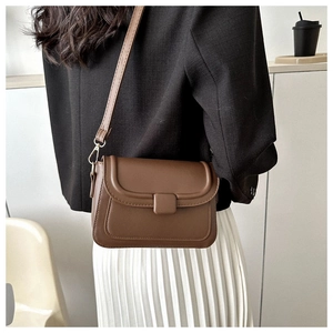 Detailed view of a vintage brown matte crossbody bag worn by a model in casual attire