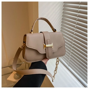Detail of khaki faux leather handbag with golden metal clasp and chain strap