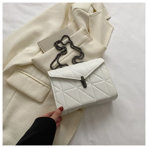 Détail du sac bandoulière blanc matelassé avec chaîne en métal sur veste en tweed