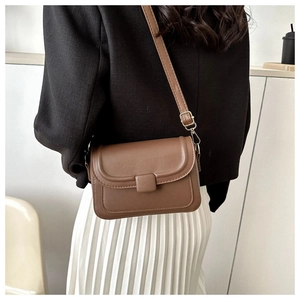 Brown leather crossbody square bag styled with black blazer and white pleated skirt