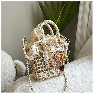 Detail of handmade woven straw bag with lace bow, floral charms and drawstring liner