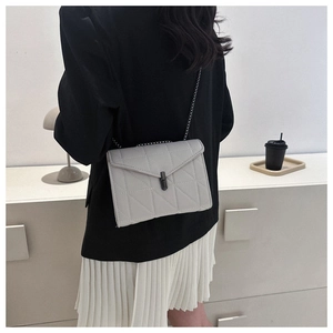 Vue arrière d'un mannequin portant un sac bandoulière matelassé gris clair avec chaîne