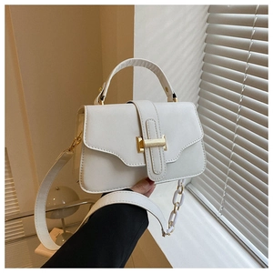 Detail of white leather handbag showing gold clasp and detachable chain strap