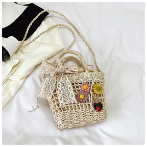 Detailed top view of handmade woven straw bag with lace bow and floral charms