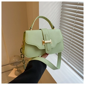 Detail view of mint green crossbody bag with golden H-clasp and decorative chain link