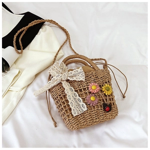 Detail of handmade woven straw bag with white lace bow and decorative floral accents