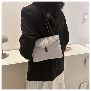Sac bandoulière matelassé argenté porté par un mannequin avec couture en losange