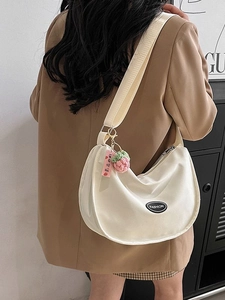 Cream crescent shoulder bag with wide strap and cute strawberry charm accessory