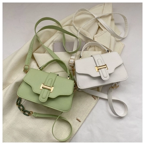 Flat lay of green and white square crossbody bags with metal hardware on a beige blazer