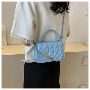 Vista dettagliata della borsa trapuntata azzurra con finiture dorate su una modella