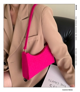 Detail of rose red textured underarm bag with gold hardware on khaki suit