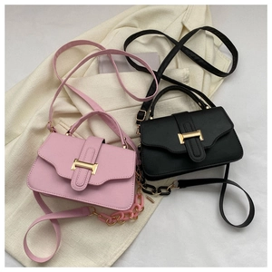 Detail of pink and black crossbody square bags with gold buckles on a beige blazer