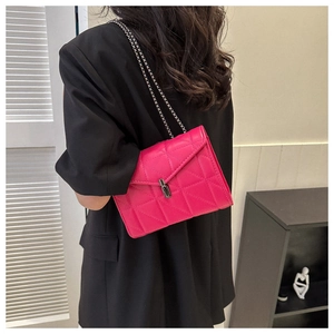Gros plan d'un sac à chaîne matelassé rose rouge avec fermoir argenté sur veste noire