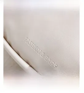 Close-up of beige leather texture with Fashion & Bags embossed logo on the square bag