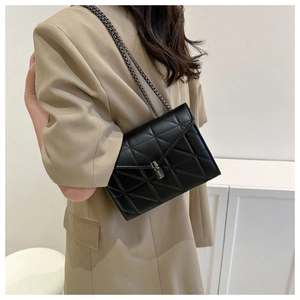 Détail du sac à chaîne matelassé noir avec fermoir métallique porté par un mannequin