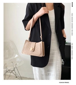 Detail of beige crocodile embossed baguette bag with a stylish round wooden buckle decoration