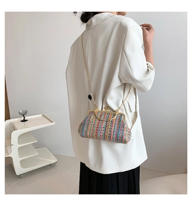 Detail of multi-color woven crossbody bag with gold heart clasp and chain strap